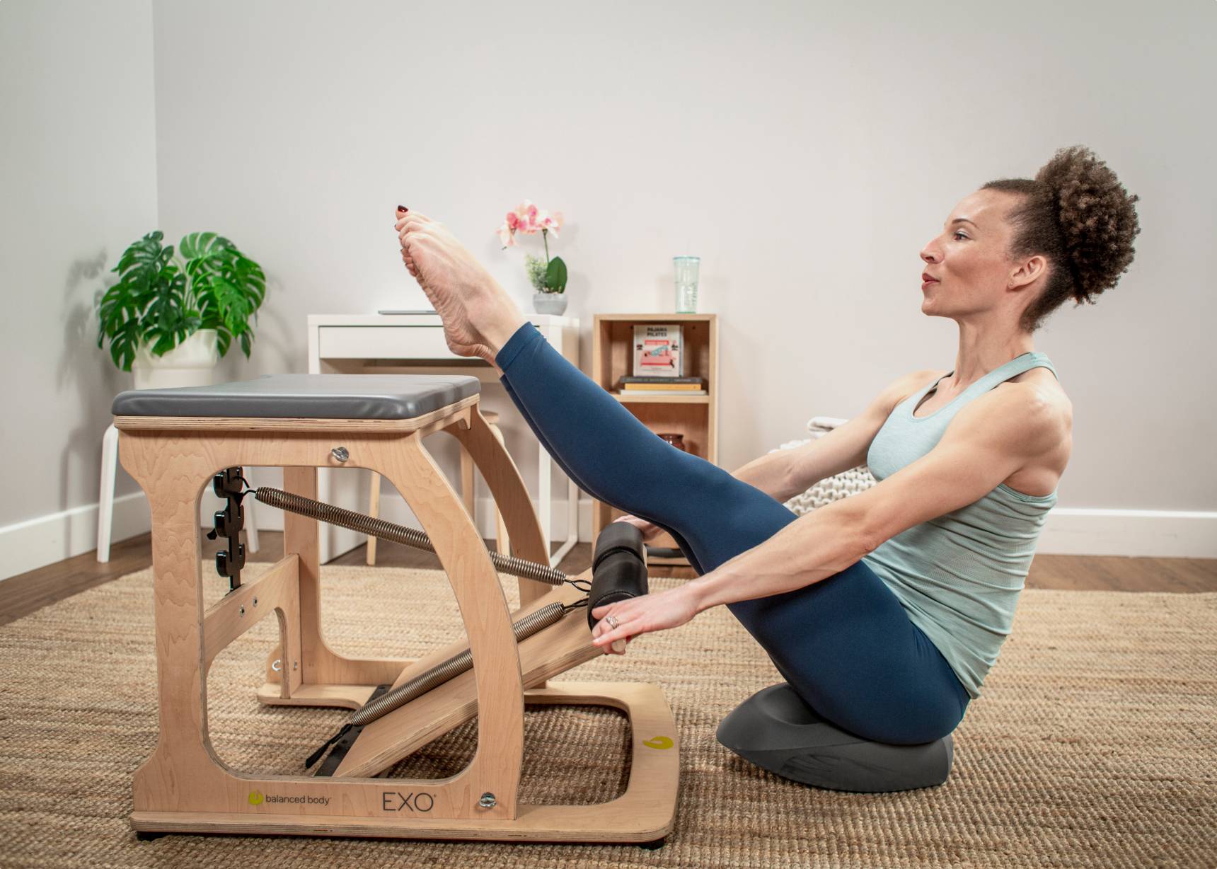 Woman working out with a Balansit cushion and an EXO chair.