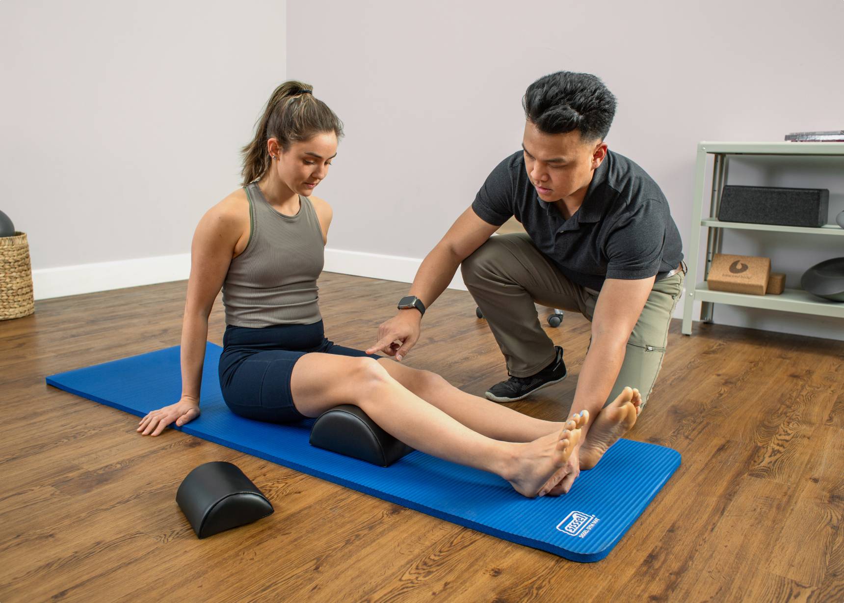 Instructor helping a student to correctly position a half-cylinder cushion for maximum benefit.