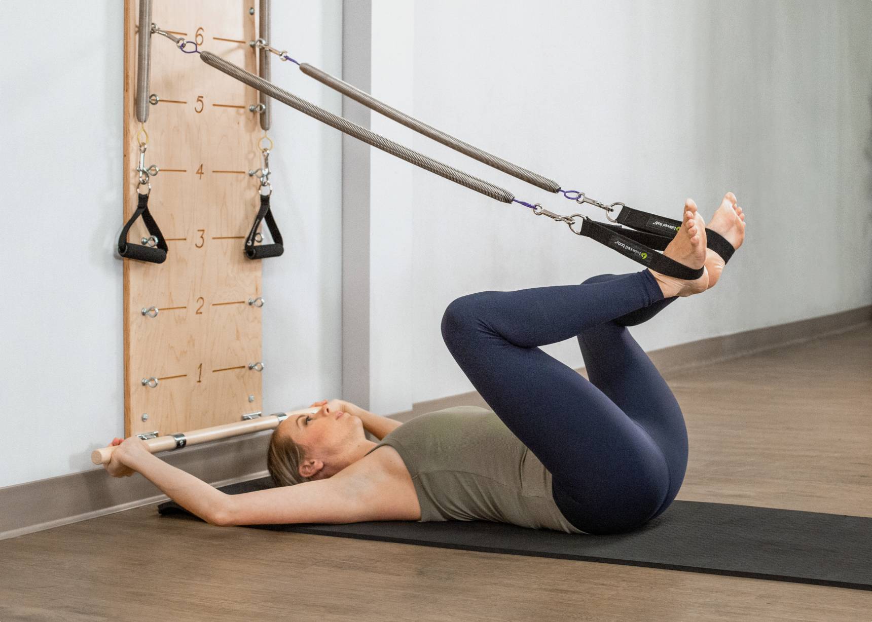 A woman engaged in a guided workout session using a springboard designed for Pilates exercises.