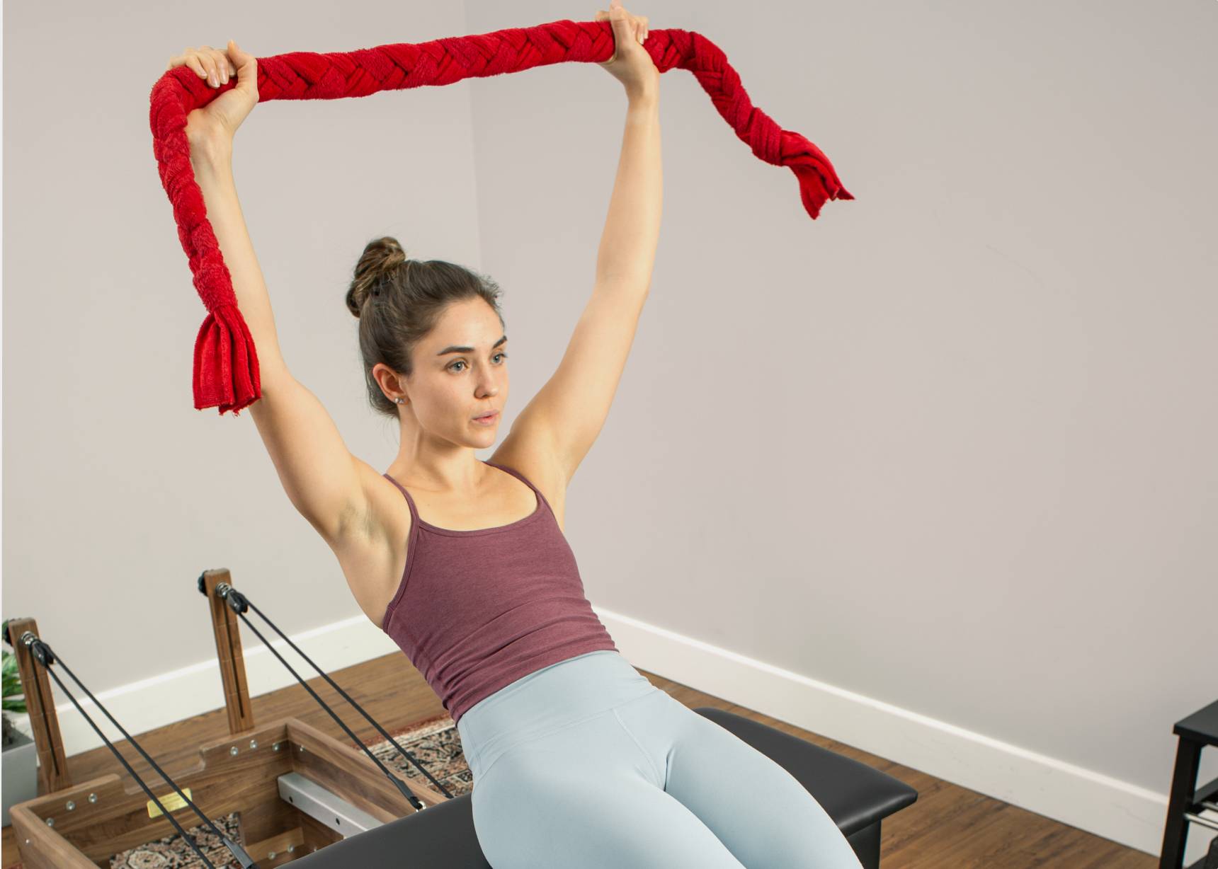 A woman gripping a red towel designed for Pilates strength and stability exercises.