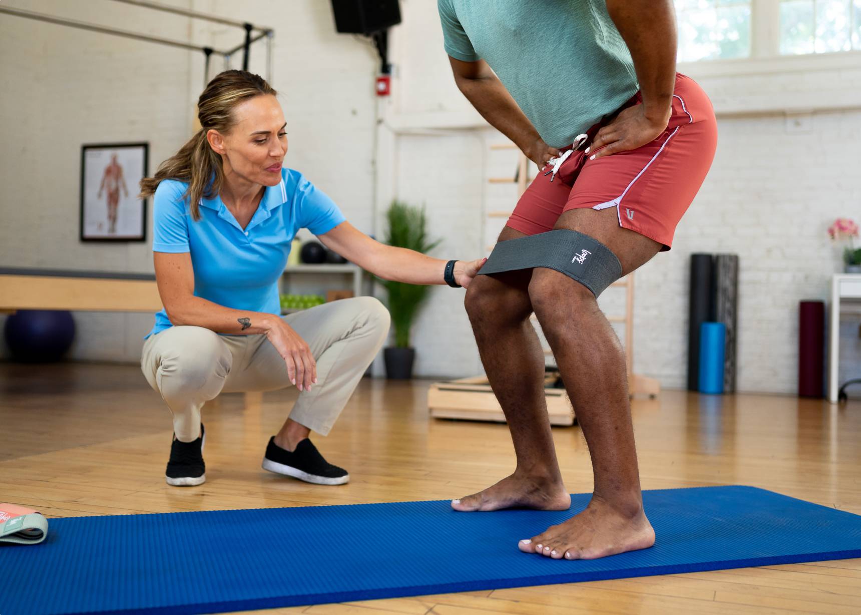 A man stretching his torso using a durable resistance band on a blue mat.