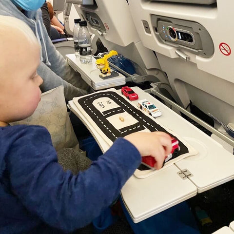 toy car storage play mat being used by a toddler on a plane