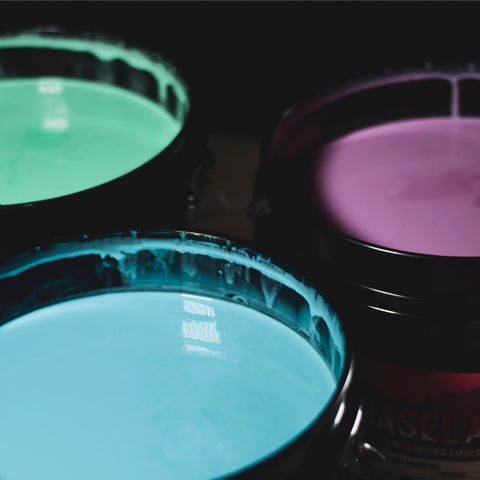 top view of gallons of emulsion. emulsion colors are pink, blue, and green