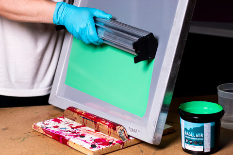 person coating a screen with a scoop coater