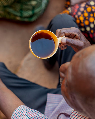 man drinking coffee on coffee farm in Rwanda