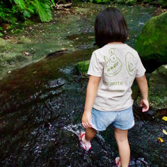 西表島の森の中、図鑑Tシャツを着て清流の側を歩く女の子