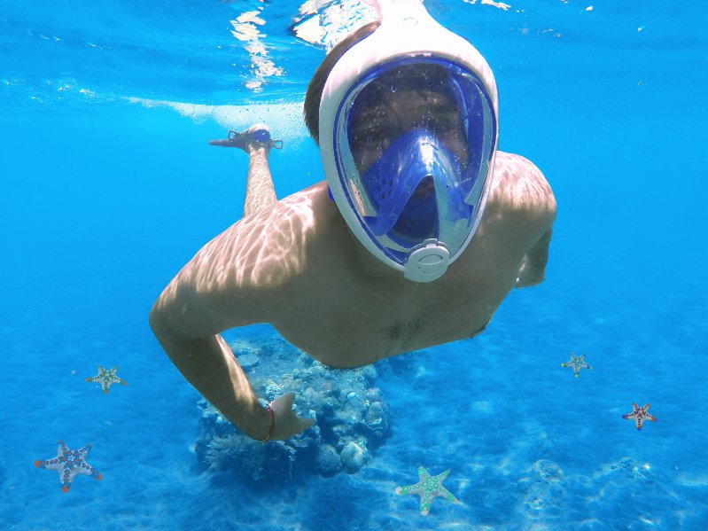 a man swimming and wearing a full-face snorkel mask in the ocean