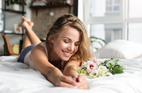 woman in bed holding flower on silky buttery soft 100% bamboo viscose sheets