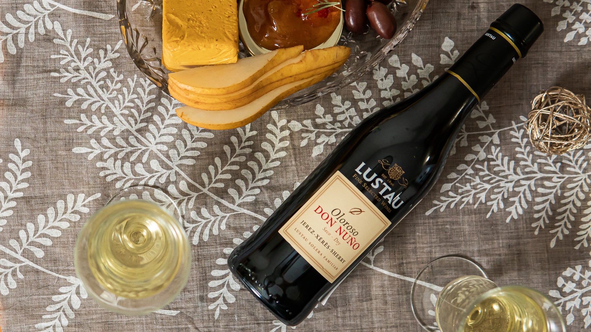 Oloroso sherry bottle with cheese platter on a table cloth and wine glasses