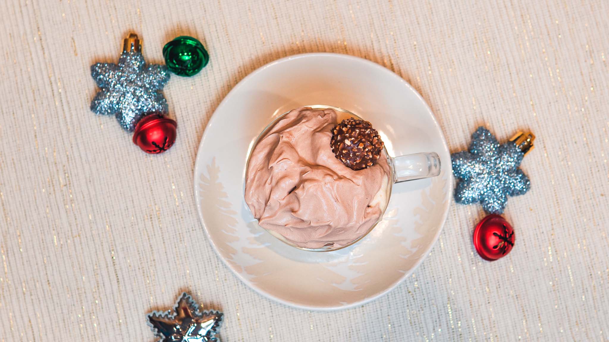 Hot chocolate shaft cocktail with christmas and holiday decor surrounding the cocktail in a mug