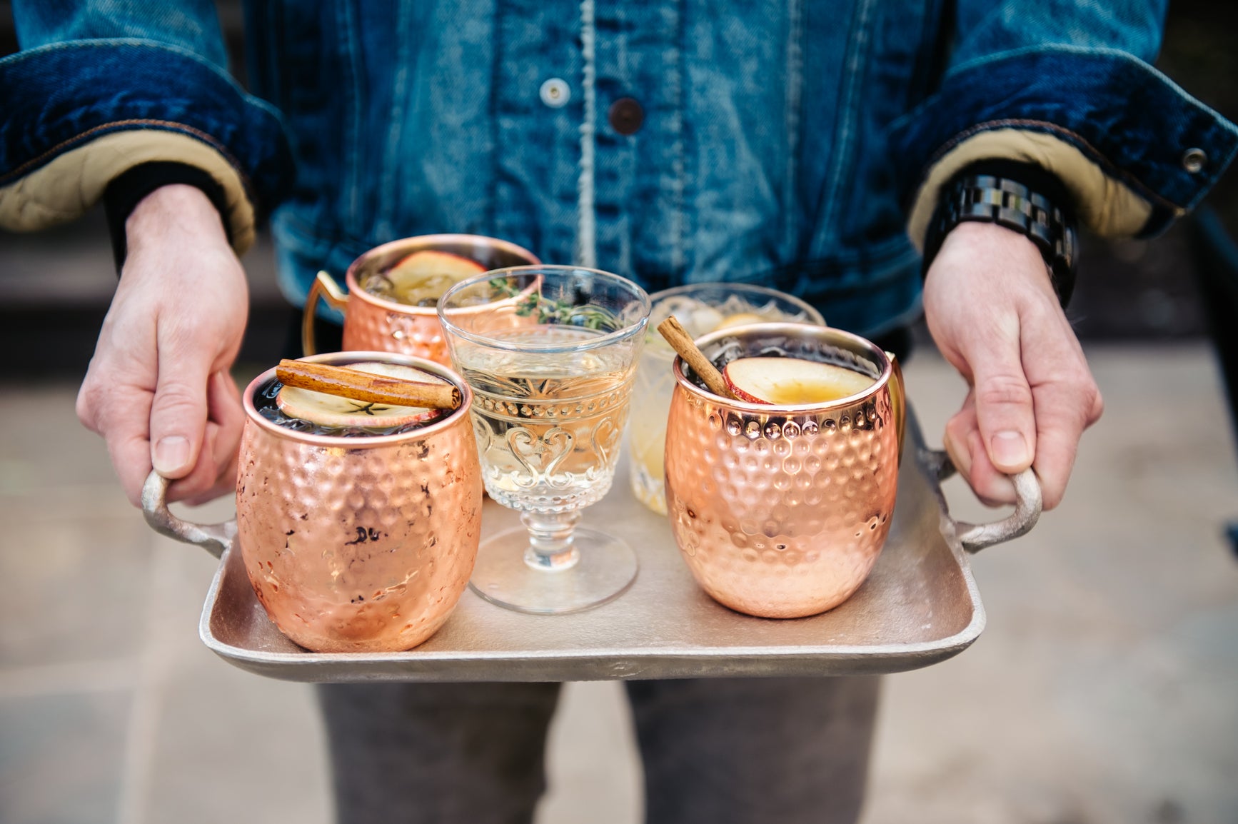 Serving non-alcoholic cocktails in a copper mug and glasses on a tray by a Caucasian man