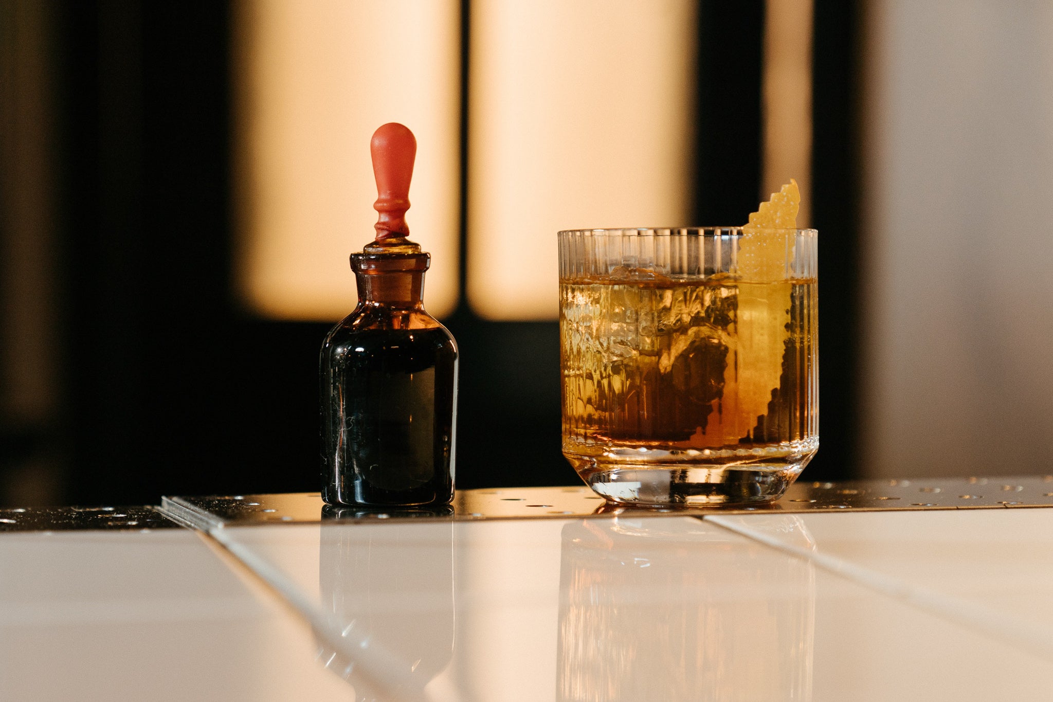 Bitters tincture glass beside an old fashioned