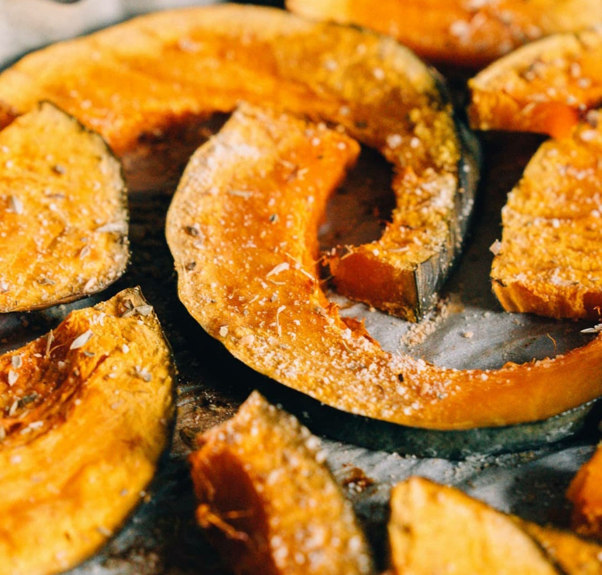 Roasted squash with parmesan with spices on a baking sheet close-up
