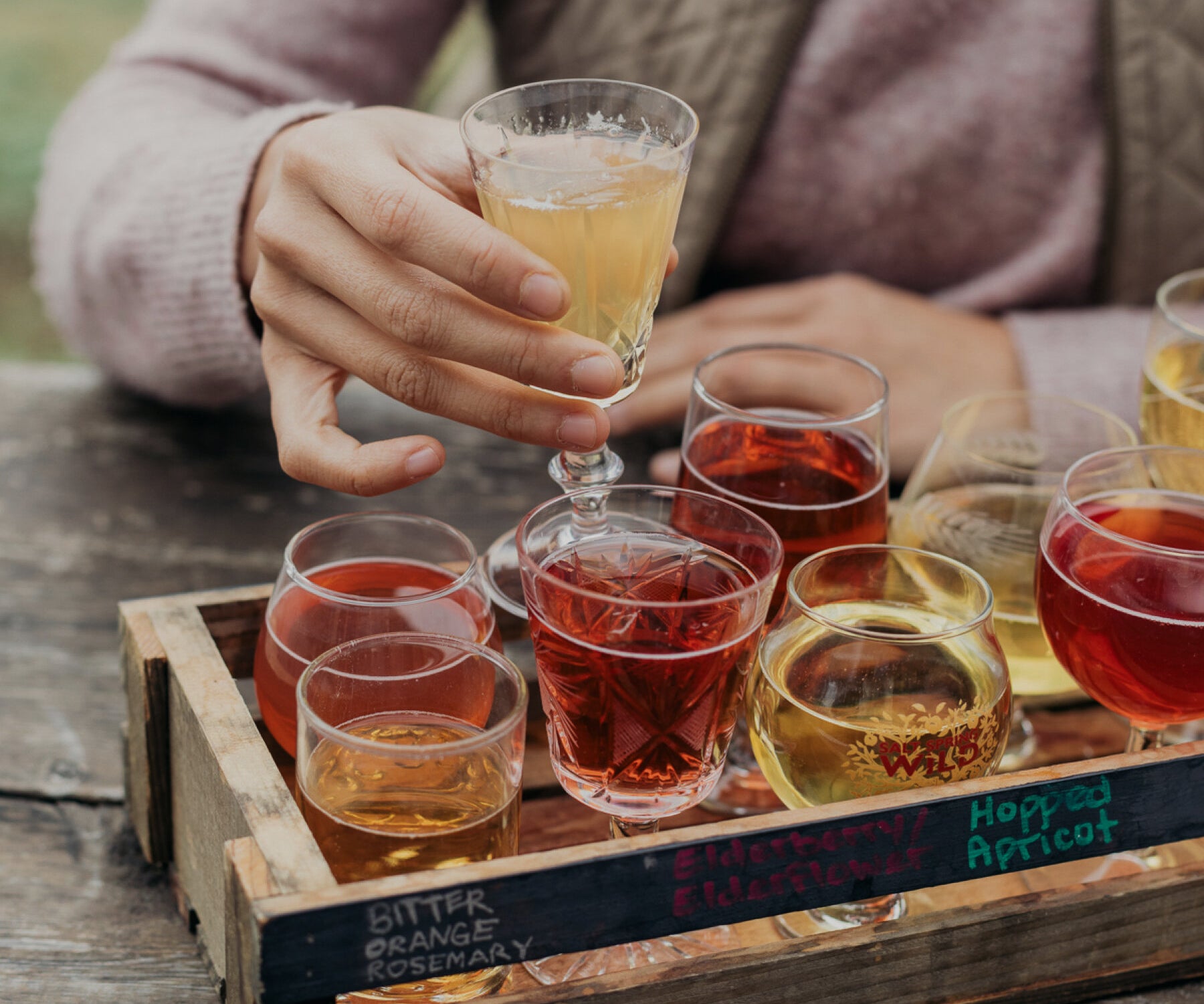 Salt Spring Wild Cider on Salt Spring Island has delicious cider flights, placed in mismatched glassware, pictured is a woman taking one to sip