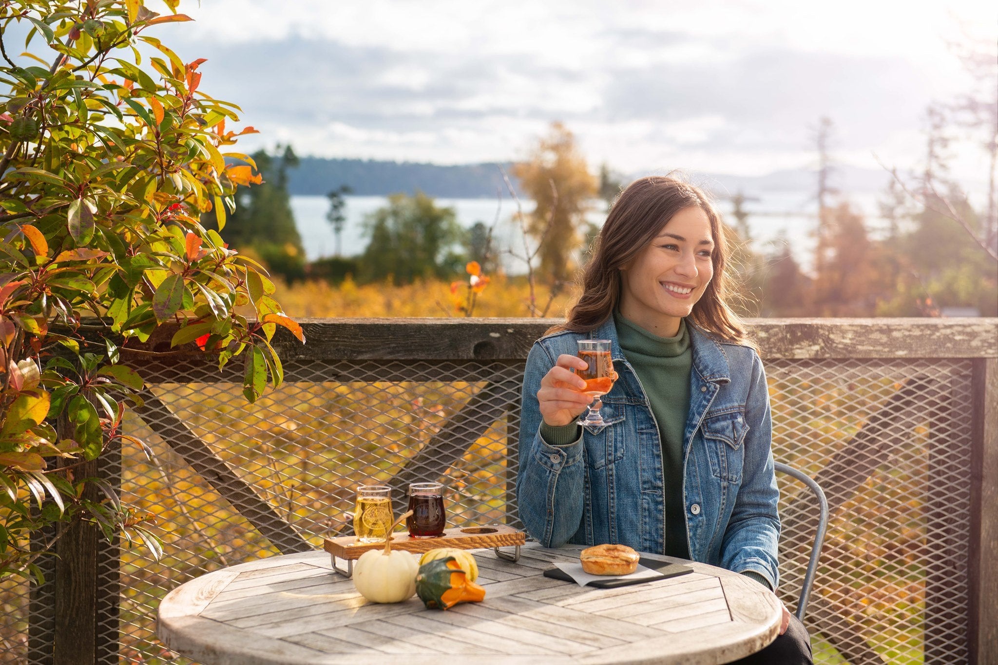 Woman enjoying cider outside on the patio at Sea Cider Farm and Cider House located outside of Victoria, British Coumbia