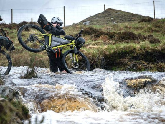 Ross O’Reilly fording a deep stream bikepacking