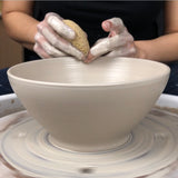 Hands wheel throwing a white stoneware Buddha bowl