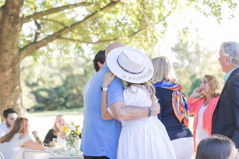 bride to be hugging dad at bridal shower wearing personalized bride hat