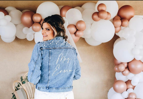 bride to be wearing personalized bride jacket with pearls at bridal shower