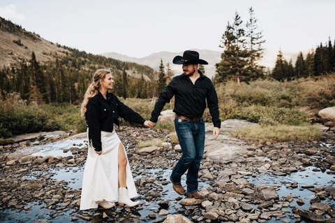 Husband and wife at vow renewal. Wife is wearing white dress with black bride denim jacket and husband is wearing black cowboy hat