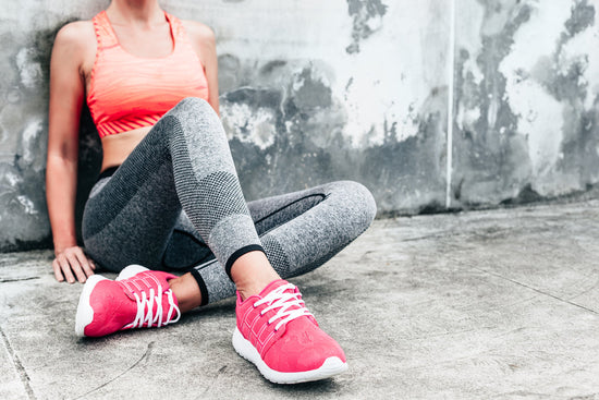 Frau sitzend an der Wand im sportlichen Outfit