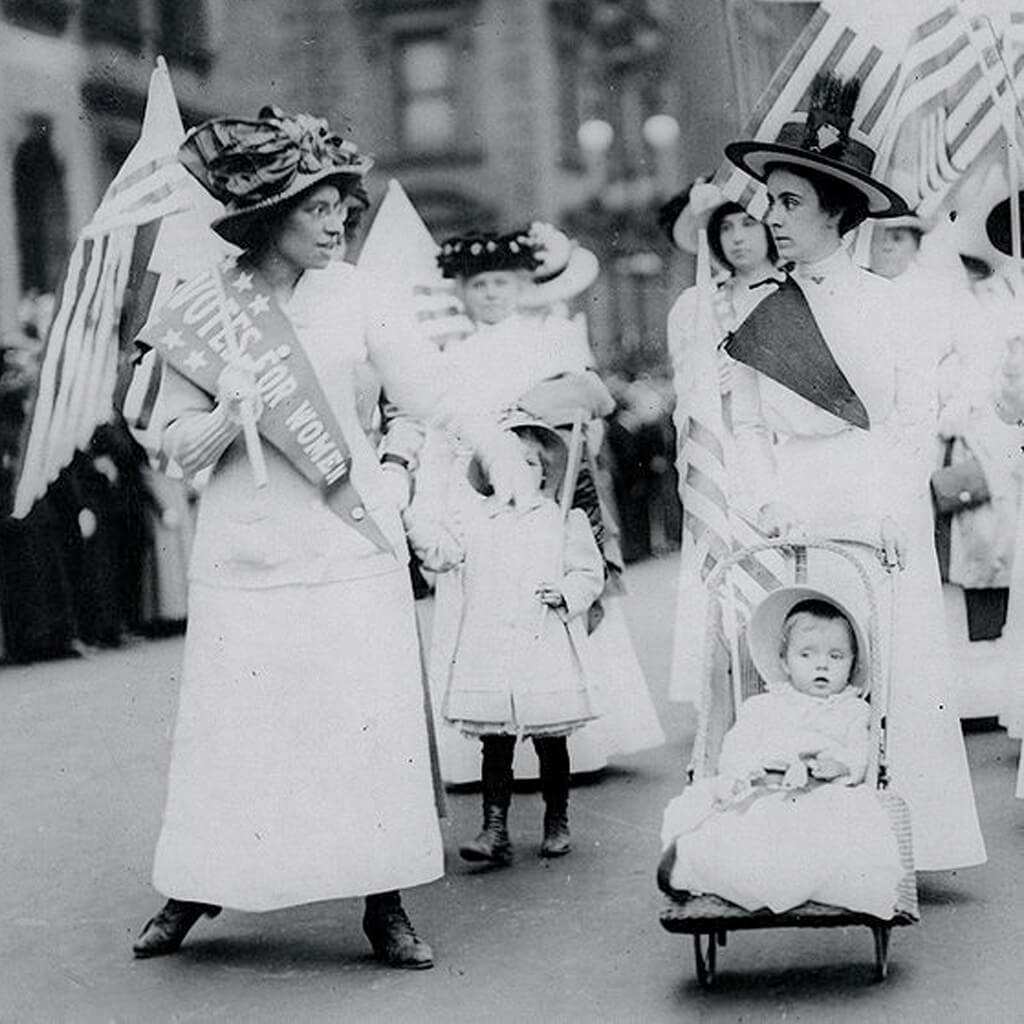Women wearing white marching with flags
