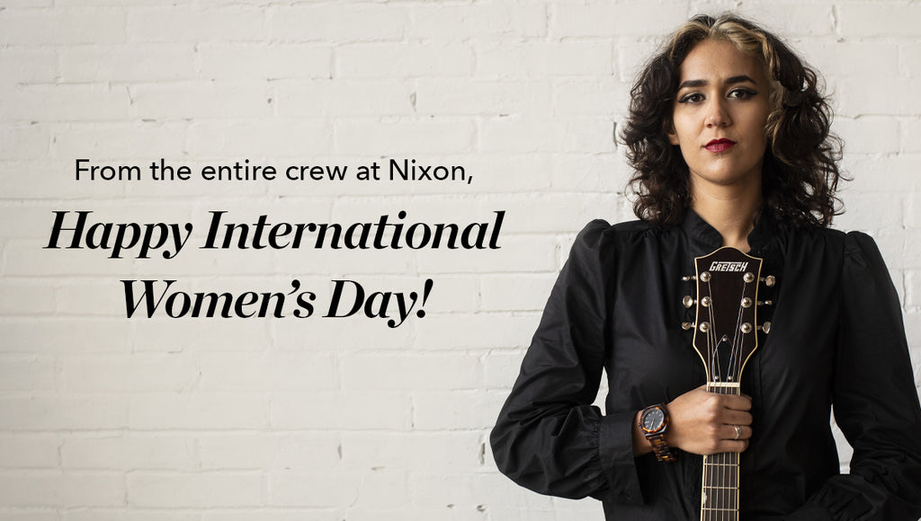 Women wearing a Nixon watch and holding a guitar with Women's Day message