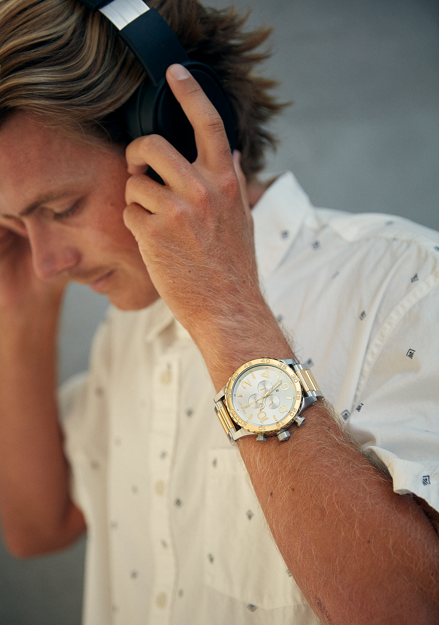 Man wearing a Nixon 51-30 Chronograph watch wearing headphones and playing music