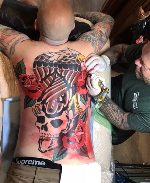 Nicholas Henriksen in the act of tattooing a back