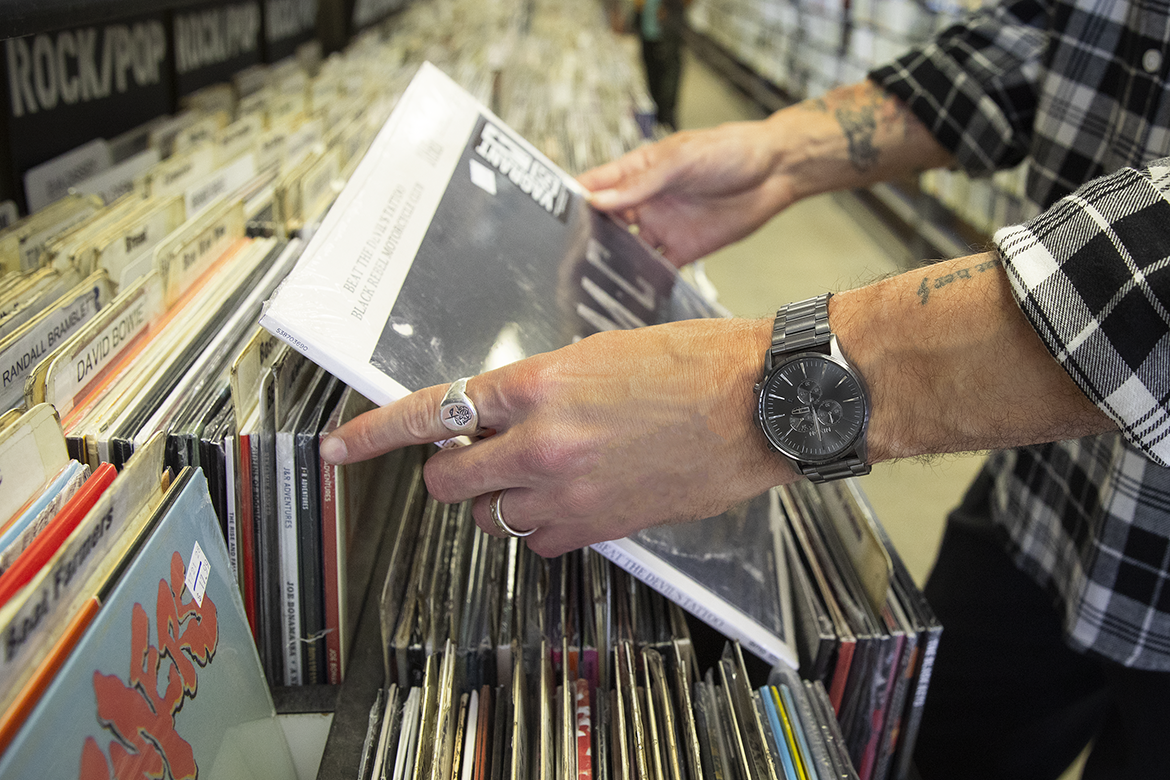 Man wearing a Nixon Sentry chronograph watch looks through records