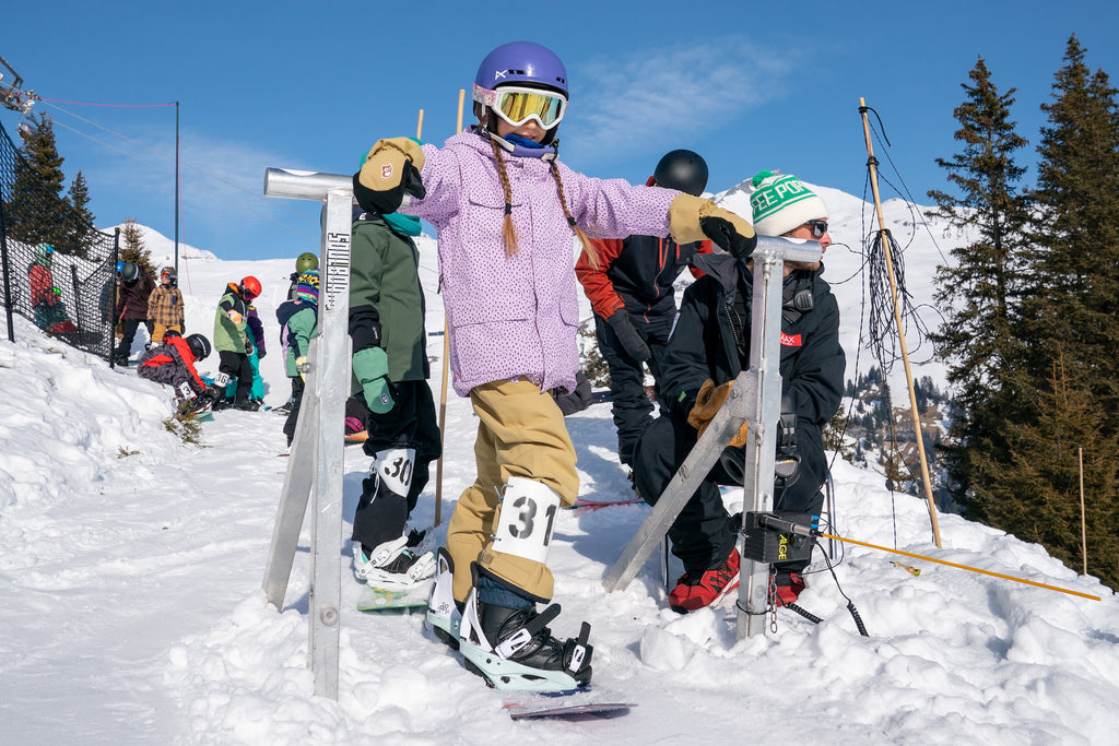 A young girl prepares to snowboard