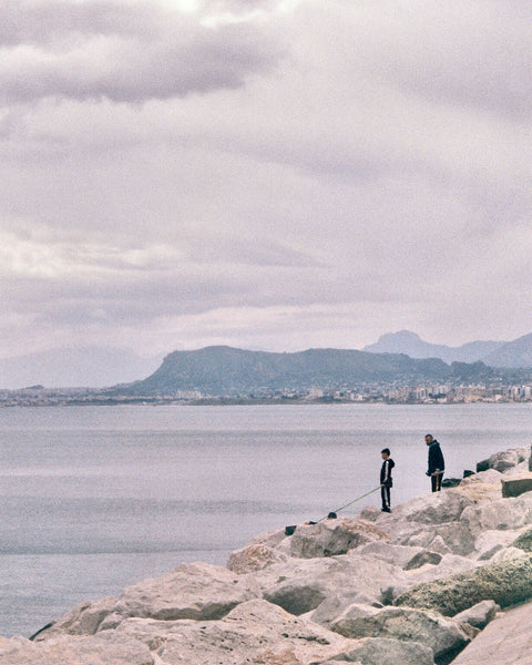 Photograph looking out over water at people standing on a rocky coast