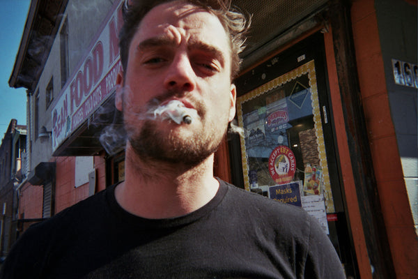 Photograph of person smoking outside a food mart