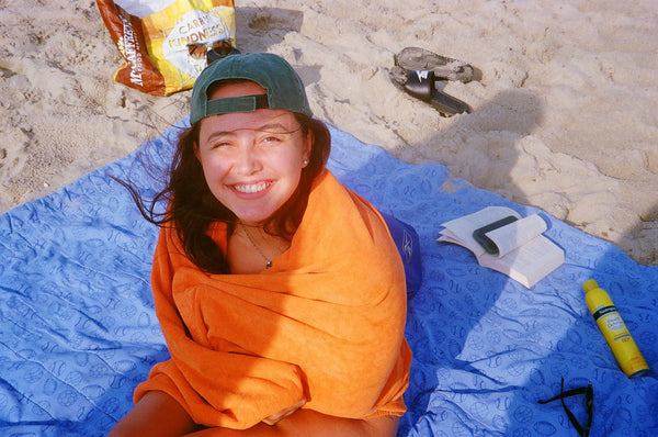 Photograph of person on a beach wrapped up in a blanket