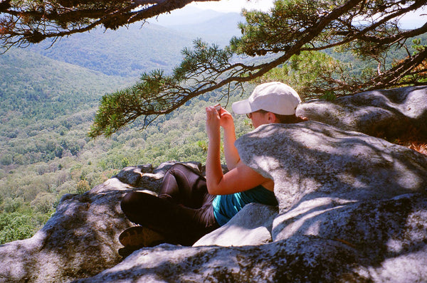 Photograph of someone sitting on a rock overlooking a vista