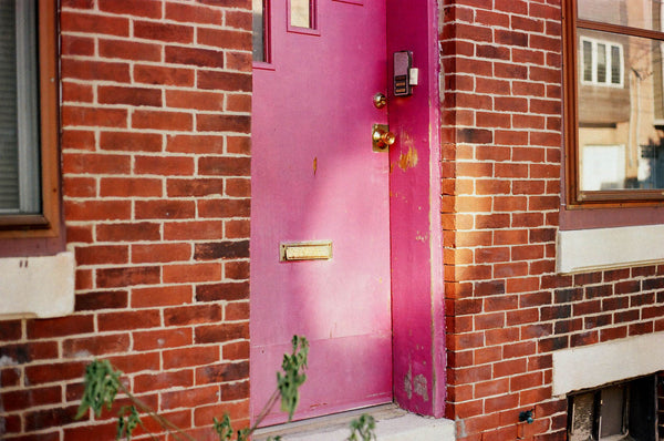 Photograph of a pink door off of a sidewalk