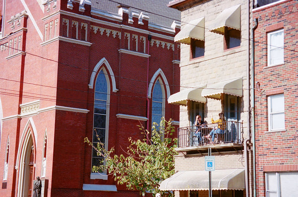 Photograph of buildings and people sitting on their balcony