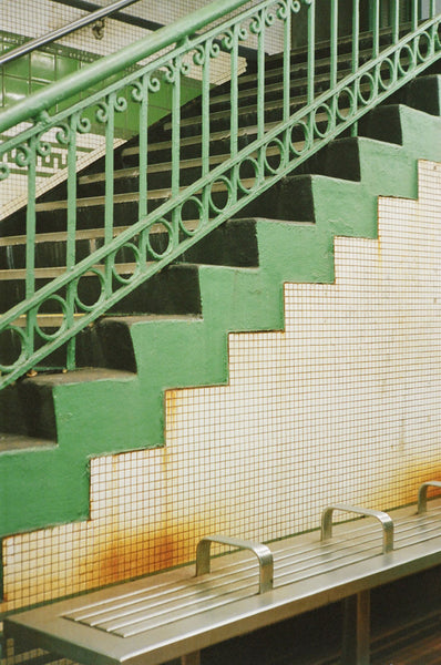 Photograph of green and white tiled steps leading up out of subway stop