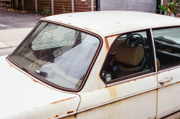 Photograph of a beat up white car