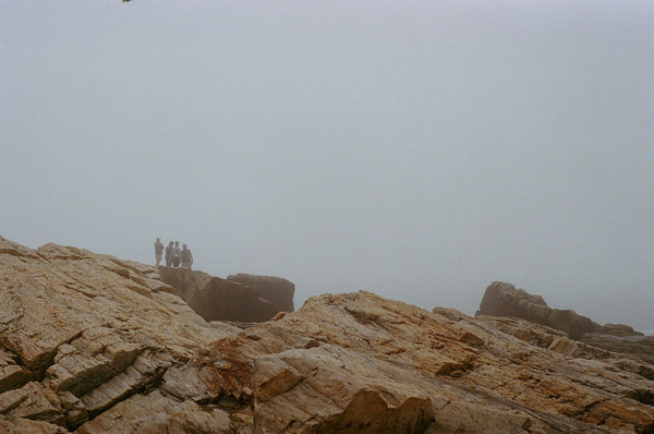 Photograph taken with a Pentax ME camera of people standing on rocks in dense fog