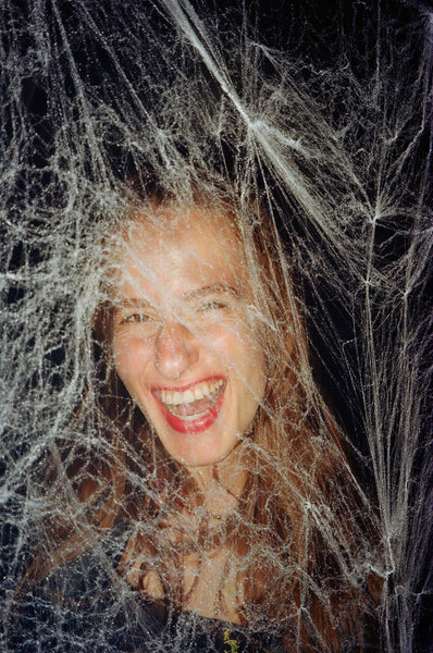 Photograph of someone standing behind fake cobwebs