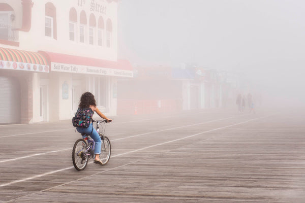 image of girl biking on ocean city boardwalk in the fog