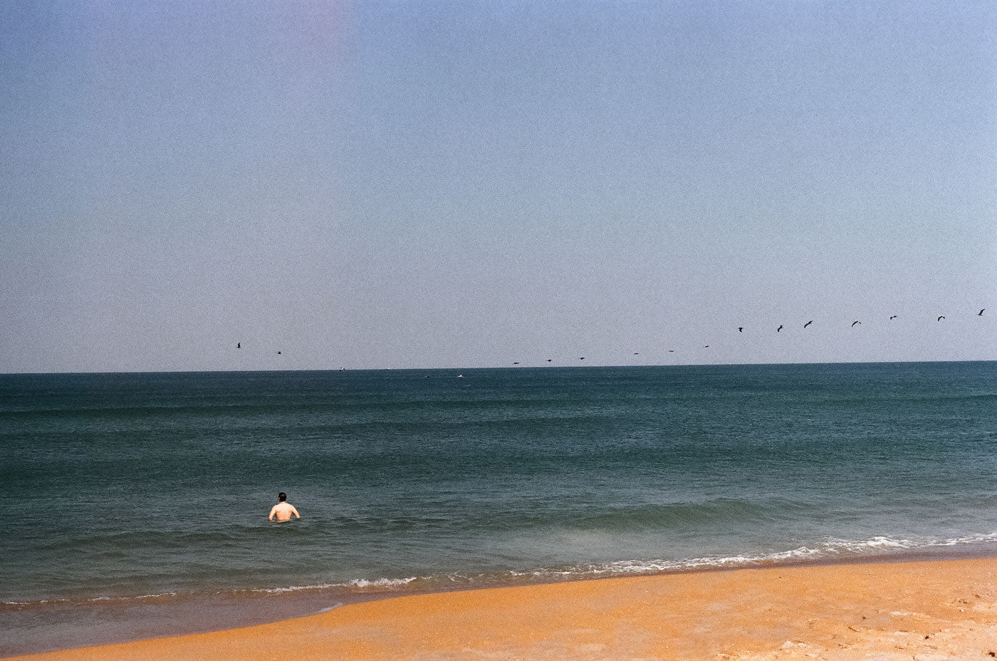 Photograph of person standing in the ocean on a beach