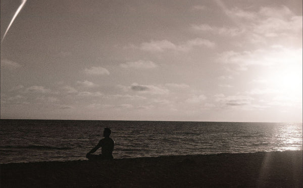 Photograph of person mediating on a beach