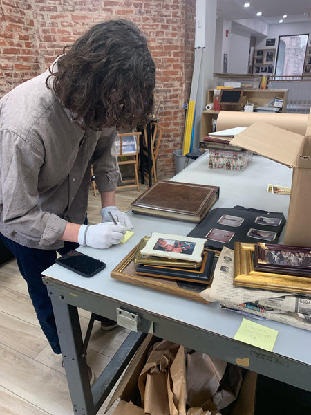 Worker sorting through personal photographs before digitizing