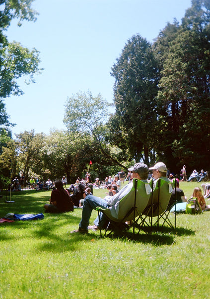 Photograph of people sitting in camp chairs in a park