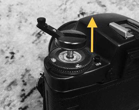 lifting the rewind knob of a SLR camera with an arrow pointing up