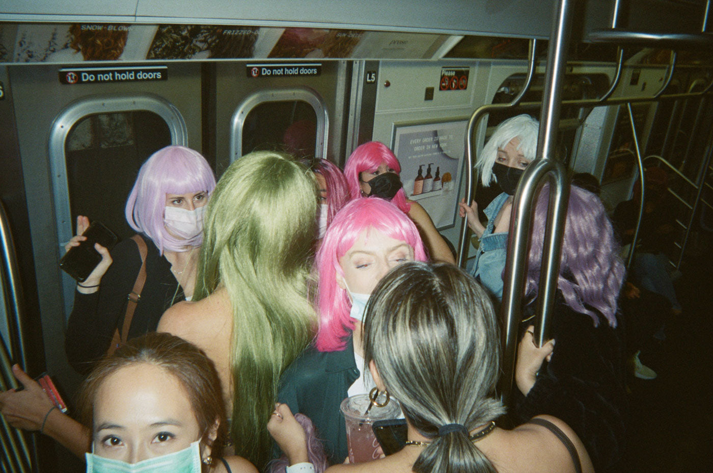 Photograph taken on subway of people wearing colorful wigs