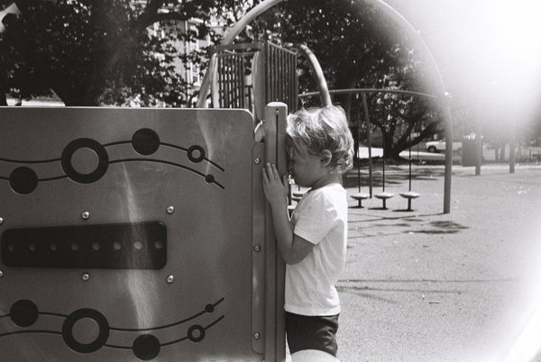 Photograph of child leaning against a playground structure