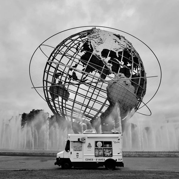 Brightened black and white photograph of ice cream truck in front of world sculpture